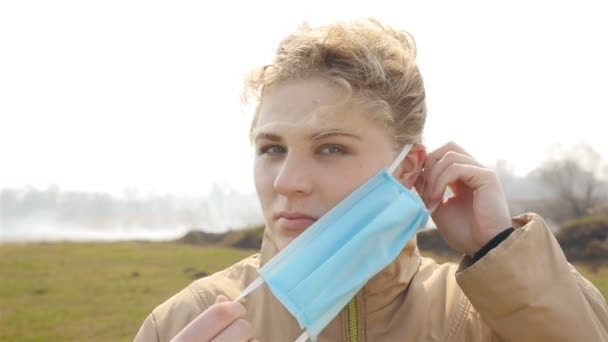 Serious girl puts on a medical mask. Polluted environment. Smoking field — Stock Video