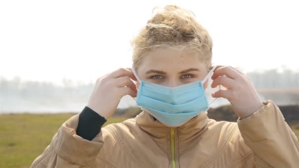 Girl near a smoking field in a medical mask. Close-up — Stock Video