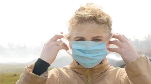 La niña se protege del humo alrededor de la máscara médica. En cámara lenta. Primer plano — Vídeo de stock