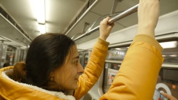 Menina bonita está de pé em um carro de metrô. Close-up — Vídeo de Stock
