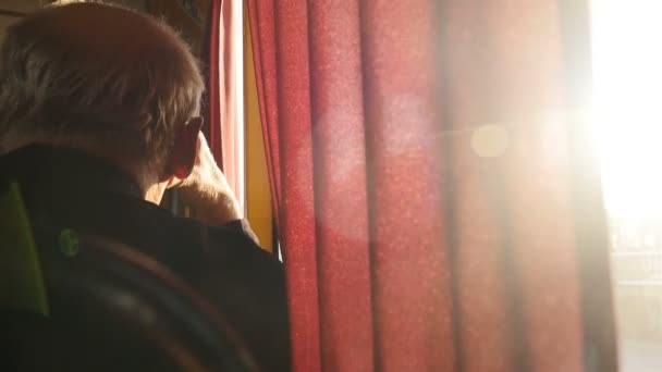 A man sits near a window in public transport. Bright rays of the sun. Close-up — Stock Video