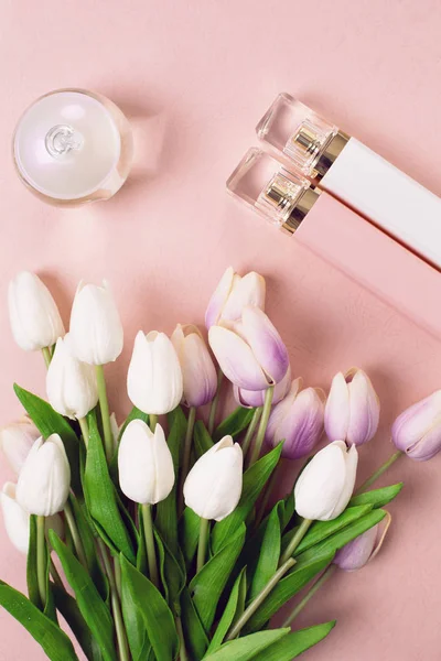 Frascos de perfume rodeado por flores sobre fundo rosa — Fotografia de Stock