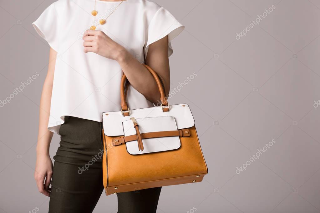 Stylish woman in modern clothes with bright orange white handbag