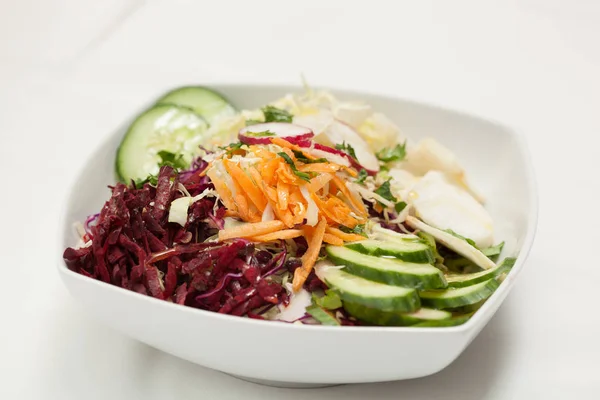 Gemengde groente salade in een witte kom op witte achtergrond — Stockfoto