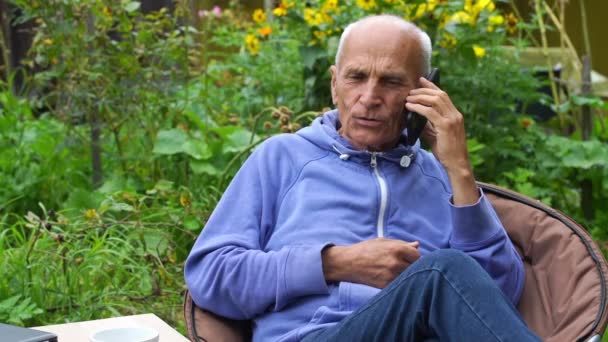 Senior homme parle au téléphone et sirote du thé en plein air vue de près — Video