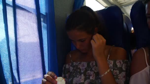 Flicka sätter på hörlurar och delar en i tåget närbild — Stockvideo