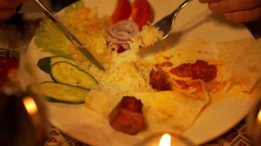 Kadın çatala pilav koyar, salatalık dilimlerinin yanına bıçak kullanır.