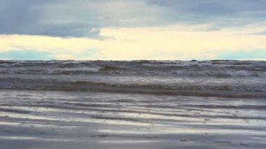 Büyük deniz dalgaları kumsalda yuvarlanır ve köpük oluşturur.