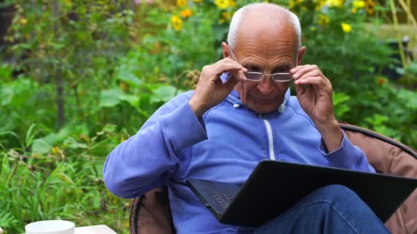 Hombre mayor cansado se quita las gafas de trabajo en el cuaderno — Vídeos de Stock