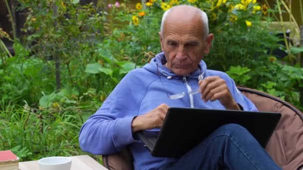 Senior man zet opzij bril en nadenkt slow motion — Stockvideo