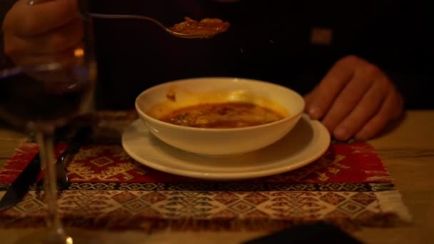 Człowiek je pyszne grube zupy z białego talerza na serwetce — Wideo stockowe