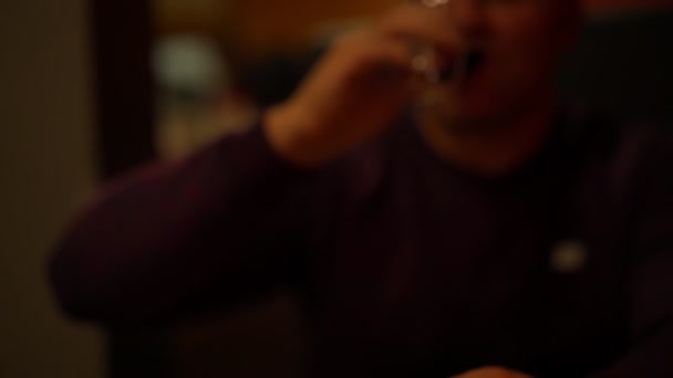 Zamazany mężczyzna w ciemnych napojach czerwone wino i stawia szklankę na stole — Wideo stockowe