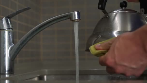 Männerhand mit gelbem Schwamm wäscht Edelstahl-Wasserkocher in Spüle — Stockvideo