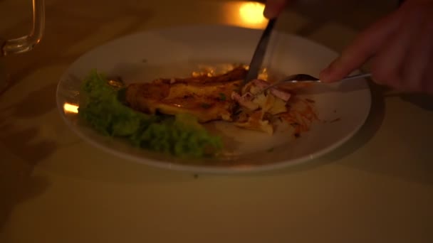 Человек режет стейк лосося расплавленным сыром при свечах — стоковое видео
