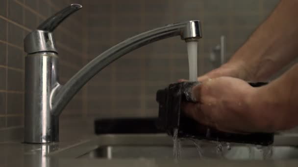 Muž myje pečlivě černé plastové kávovar blok — Stock video