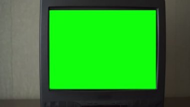 Parlak yeşil renkli anahtar ekranlı TV seti duvarda duruyor
