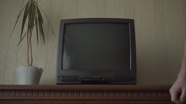 Мужчина заглушает каналы на телевизоре с рябью на экране — стоковое видео