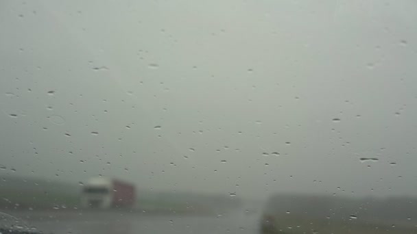 Små regndroppar faller på bilens vindruta och torkare rör sig — Stockvideo