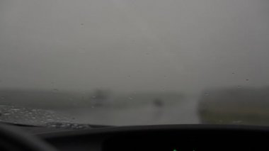 Bulanık arabalar ön camın dışında sağanak yağmurda yolda gidiyor.