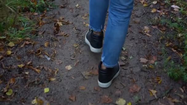 Kvinna bär blå jeans och svart läder sneakers går — Stockvideo