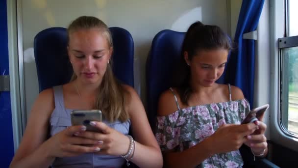 Χαριτωμένο κορίτσι δείχνει εικόνα στο τηλέφωνο σε φίλο στο κοντινό τρένο — Αρχείο Βίντεο