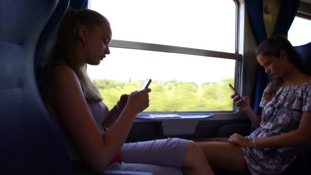 女の子は都市間雨の中で座っている電話でソーシャルメディアを使い — ストック動画
