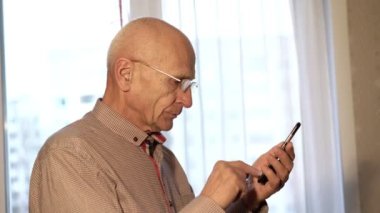 Gözlüklü, kırmızı tişörtlü, akıllı yaşlı adam telefonda.