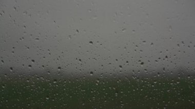 Şiddetli yağmur damlaları şeffaf camlara düşer ve aşağı iner.