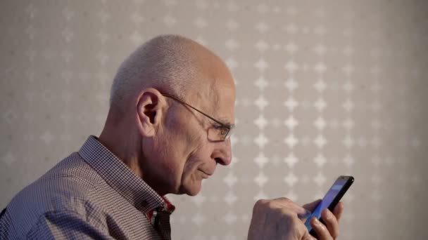 Пожилой человек в очках открывает для себя способности смартфона — стоковое видео