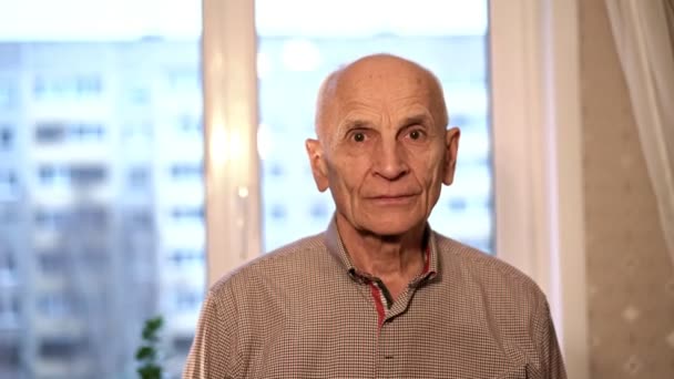 Спокойный старый лысый мужчина в клетчатой рубашке смотрит вперед — стоковое видео