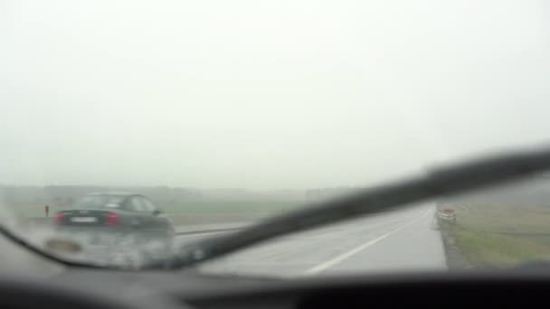 Carros dirigem ao longo da estrada molhada entre campos vista contra limpadores — Vídeo de Stock