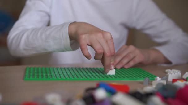 Dziewczyna w białej koszuli instaluje kolorowe plastikowe lego część — Wideo stockowe