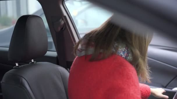 Boa mulher com cabelo loiro curto em casaco vermelho fica no carro — Vídeo de Stock