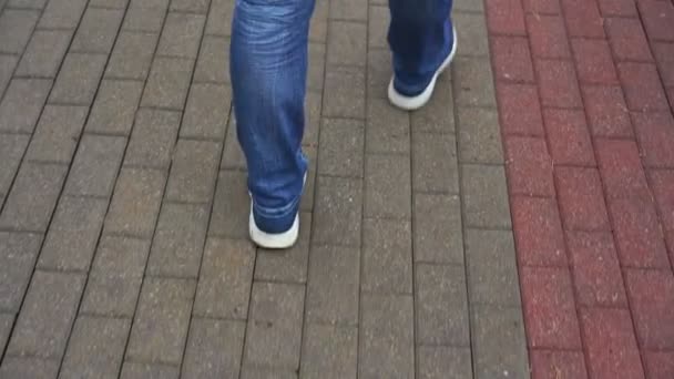 Человек в джинсах и кроссовках с зонтиком на платформе — стоковое видео
