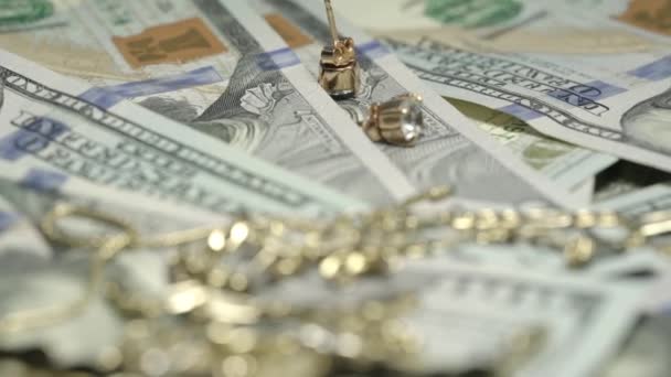 Золотые серьги браслет и ожерелье лежат на сто долларов — стоковое видео