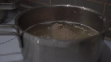 Domuz eti parçaları mutfakta ocakta metal tavada kaynıyor.