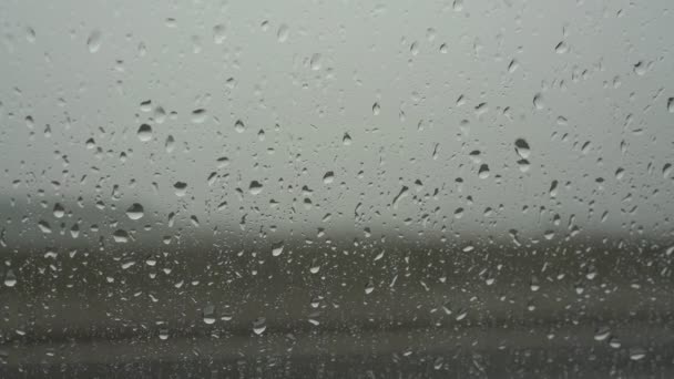 Большие капли дождя падают на автомобильное стекло крупным планом — стоковое видео