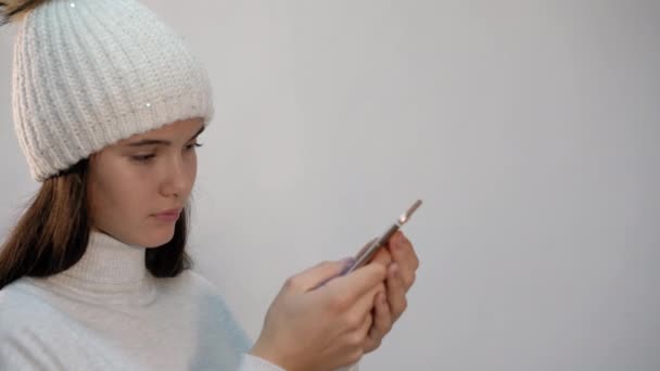 Menina no chapéu surfa internet com telefone no fundo de luz — Vídeo de Stock