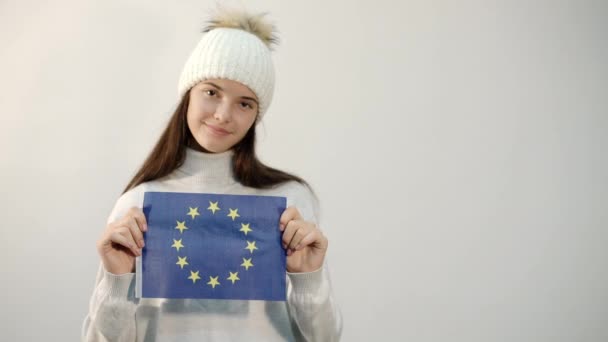 Κορίτσι με χειμωνιάτικα ρούχα κρατά σημαία της Ευρωπαϊκής Ένωσης στο στούντιο — Αρχείο Βίντεο