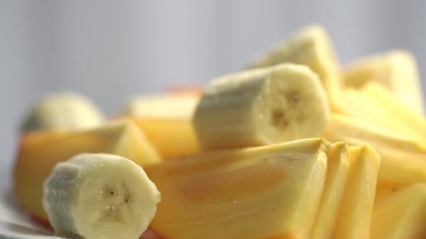 Смачні стиглі банани та шматочки хурми обертаються крупним планом — стокове відео