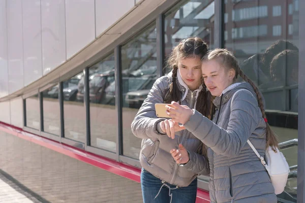 girls stand at bus stop or train station and study schedule of t