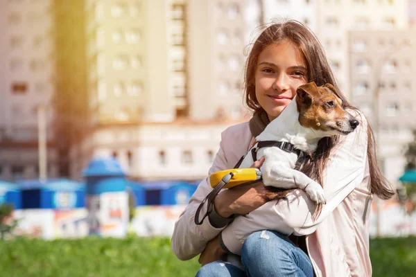 Kız çömelmiş, elinde bir köpek, Jack Russell Terrier, şehir yapımı.