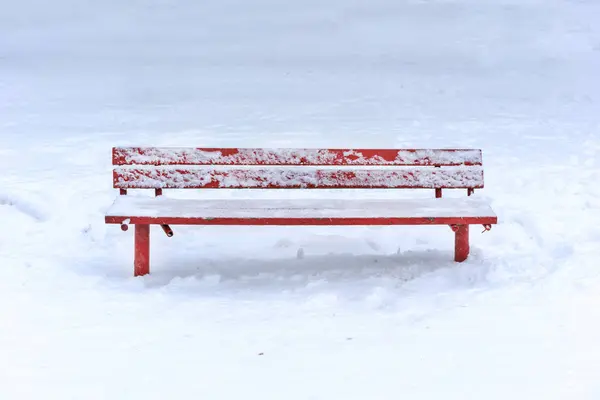 Vieux banc en bois neigeux rouge vide — Photo