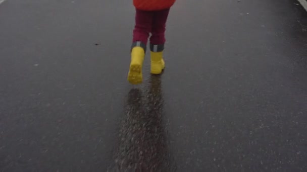 Kid legs in red pants and yellow waterproof rubber boots — Stock Video