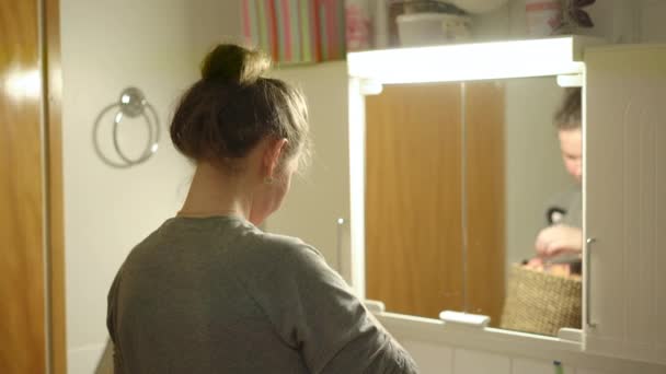 Ung kvinna tittar på lådor med kosmetika i badrummet — Stockvideo