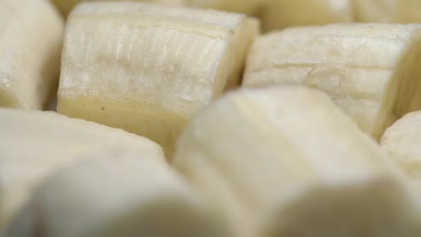 Savoureux morceaux de bananes crues mûres se trouvent sur plaque tournante gros plan — Video