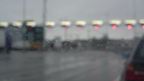 Semáforos borrosos de color rojo colgados sobre un camino gris húmedo — Vídeo de stock