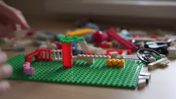 Teenager builds constructions on green flat plastic platform — 비디오
