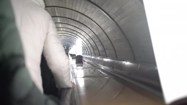 Граждане идут вверх эскалатор мимо ламп в метро тоннеля крупным планом — стоковое видео