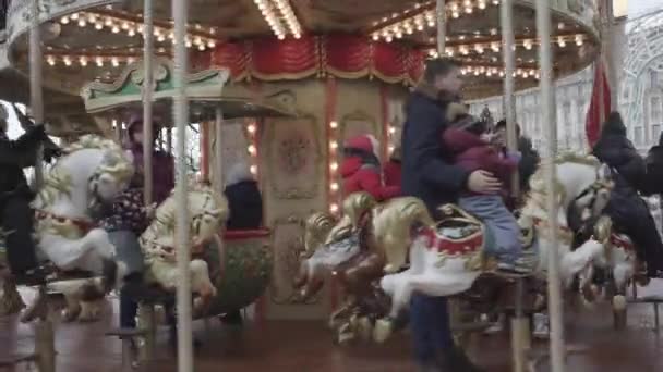Parents take photos of children swinging on carousel in park — 비디오